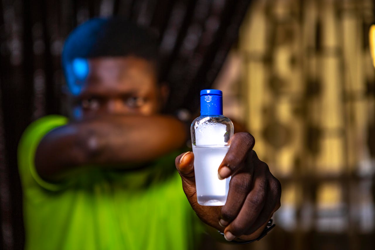 A focused portrait highlighting hygiene with a person holding a hand sanitizer bottle.