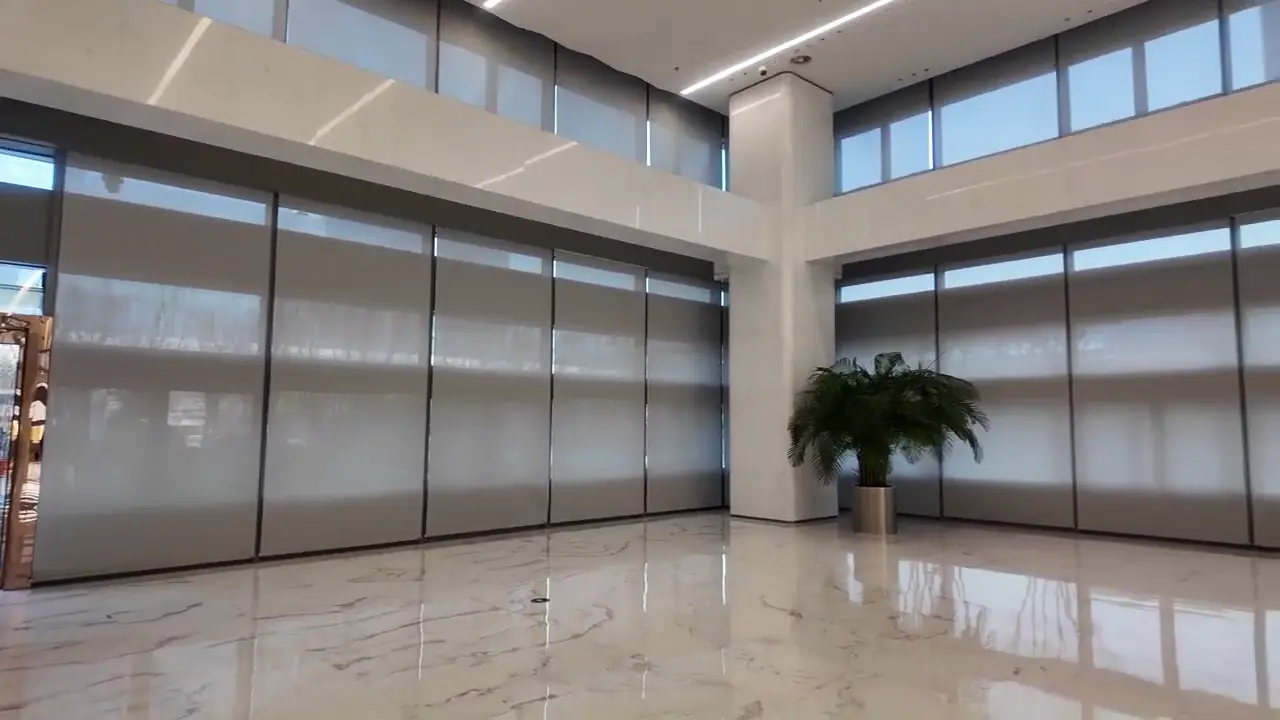 JD.com Headquarters Motorized Shading Project — Beijing Yizhuang Multiple roller shades across a double-height glazed corner.